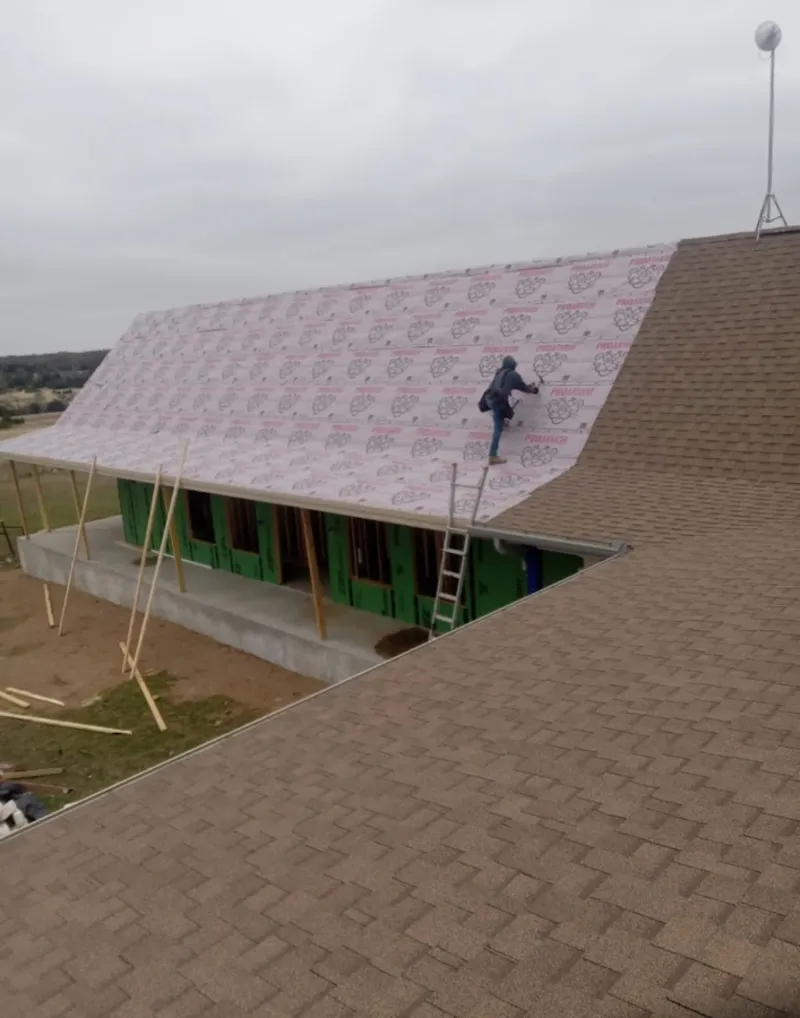 Worker preparing underlayment for a metal roof installation in Okmulgee
